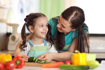Happy mother and her kid daughter enjoy making healthy meal together at their kitchen