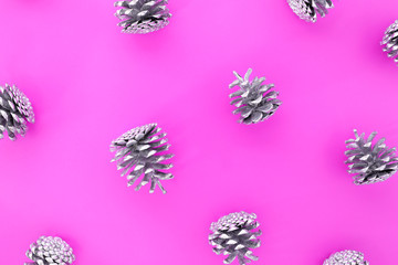 Christmas pattern. Flat lay made with many silver cones on a pink background. Top view.