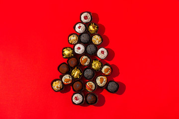 New Year concert. Handmade candies laid out in a Christmas tree on a red background. View from above.
