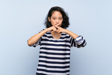 Asian young woman over isolated blue background showing a sign of silence gesture