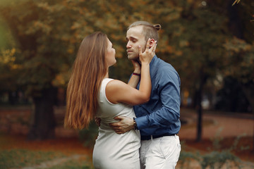 Cute couple in a park. Lady in a white dress. Man in a blue shirt