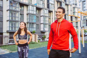 Fototapeta premium Young couple in black sports outfit doing morning workout outdoors. Young man and woman stretching they muscle before running on bridge.