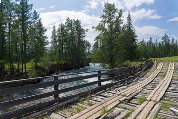 Old wooden bridge over the fast river.
