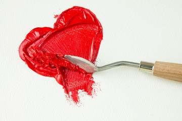 Red heart on white canvas and palette knife