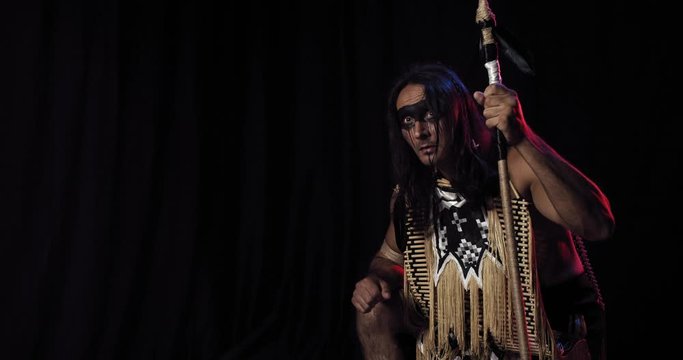Native american with a spear, wearing traditional clothes is hunting, 4k
