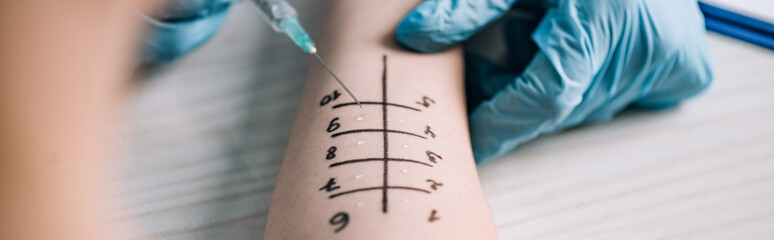 panoramic shot of allergist in latex gloves holding syringe near woman while doing allergy test in clinic © LIGHTFIELD STUDIOS