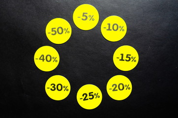 Yellow round stickers with discounts of 10 to 50 percent. Sell-out. Discounts on a black background. Black Friday. Price fall. Posters. Macro discounts.