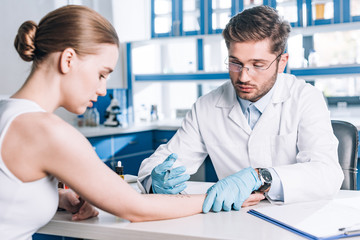 selective focus of allergist holding syringe near woman in clinic