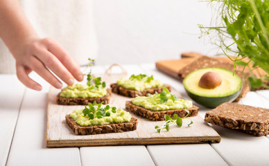 Girl preparing sandwiches with avocado spread and microgreen