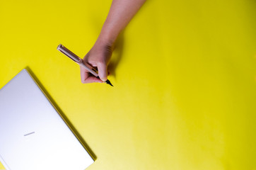 persona escribiendo sobre lienzo amarillo con pluma o bolígrafo