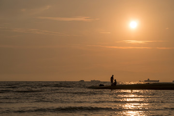Fototapeta premium Beautiful sunset nature background, unknown fisherman with net fish on beach. Father and son fishing. Family bond concept.