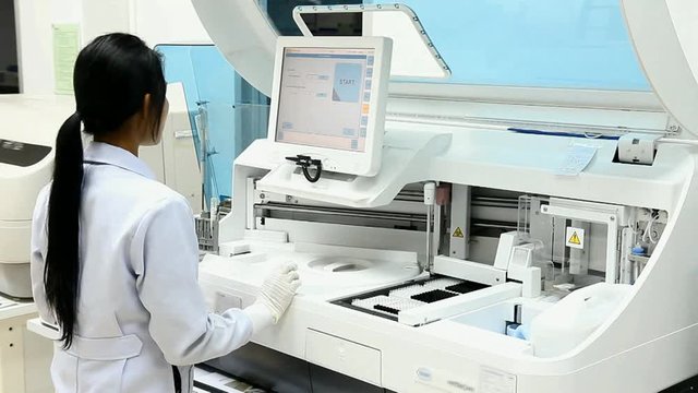 Woman working in laboratory on modern machine for blood testing.