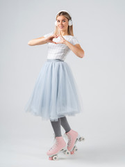 Naklejka premium Pin up woman in retro roller shoes and headphones with heart shaped hand gesture. Vertical studio shot on white background