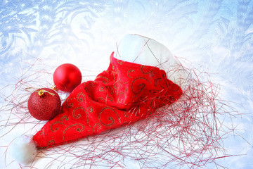 Santa Claus Cap. Sparkling shiny Christmas red baubles and tinsel. Frosty pattern on winter window glass in the background. Merry Christmas and Happy New Year 