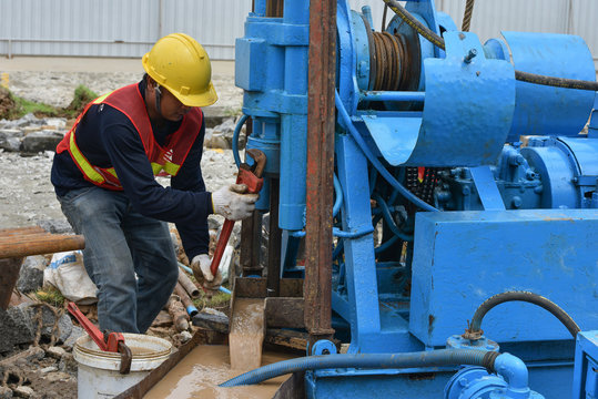Construction workers drilling obtaining soil samples field for geological logging, analysis and testing, soil investigation before design pile tip for construction site.