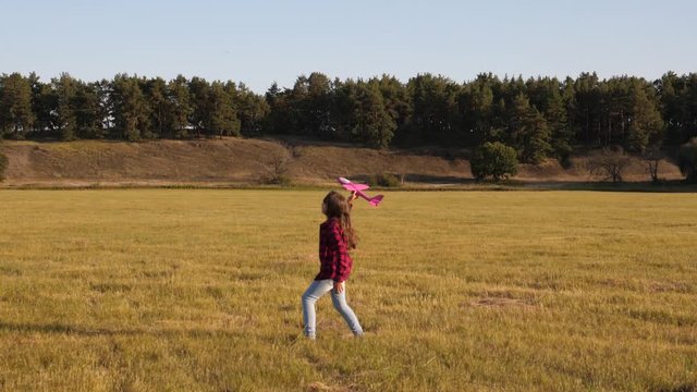 happy childhood concept. child launches a plane to the sky and smiles. teenager dreams of flying and becoming a pilot or an astronaut. Happy girl runs with an airplane toy on the field.