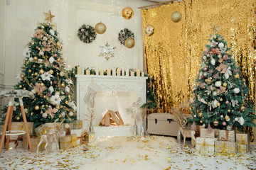 Beautiful classic golden Christmas room decor. Christmas studio interior. New Year's gifts, trees, decorations. Happy New Year. Christmas trees with New Year s balls and a garland.