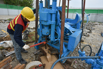 Construction workers drilling obtaining soil samples field for geological logging, analysis and...