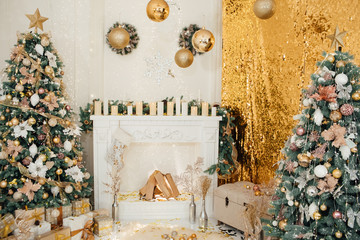 Winter New Year and Christmas decoration in white large living room. Decorated Christmas trees near sofa and classical fireplace in hall. Gifts under the tree. Cozy Christmas studio interior. 