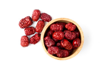 Bright red Chinese jujube in the wooden bowl and spread on a white background.
