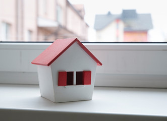 house in winter - heating system concept and cold snowy weather with model of a house wearing a...