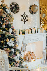 Christmas living room interior, decorated  mantelpiece, lit up trees with  gold green baubles and ornaments, stars, wreath, candles, cosy chair. Merry Christmas and Happy New Year