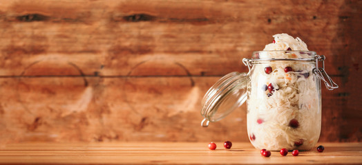 Sauerkraut in glass jar on wooden background with copy space. Fermented and marinated cabbage at home. The best natural probiotic food