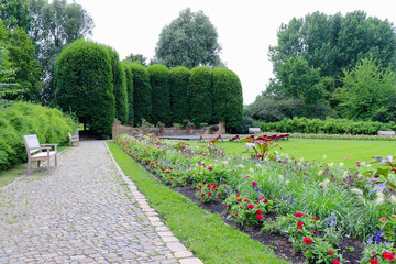 Beautiful flower bed in the park with a variety of flowers and lawn, benches for relaxation