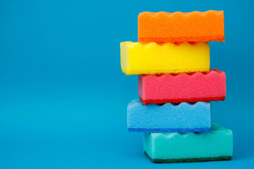 Multicolored sponges for cleaning and washing dishes on a blue background. Space for text
