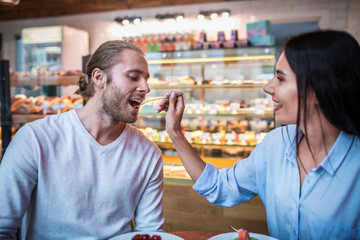 Bearded husband tasting dessert while spending morning with wife
