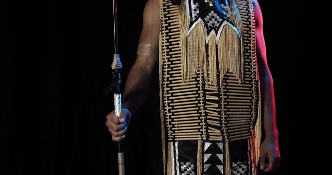 Native indian man is standing with a spear in hand, red and blue light, 4k