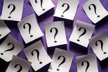 Randomly scattered question marks on white paper
