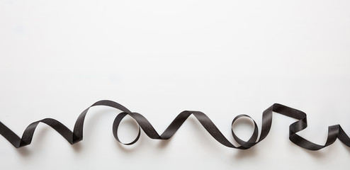 Black ribbon curl on black color background. Minimal card template