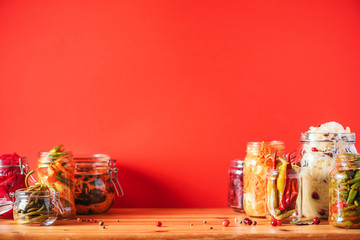 Assortment of various fermented and marinated food over wooden background, copy space. Fermented vegetables, sauerkraut, pepper, garlic, beetroot, korean carrot, cucumber kimchi in glass jars.