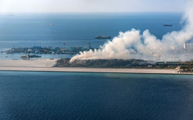 Aerial view of waste disposal site on the island. Burning garbage heap of smoke from a burning pile of refuse on island. Garbage dump yard in Male Atoll Maldives, Asia.