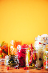 Assortment of various fermented and marinated food over wooden background, copy space. Fermented vegetables, sauerkraut, pepper, garlic, beetroot, korean carrot, cucumber kimchi in glass jars.