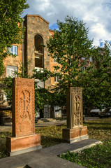 Fototapeta na wymiar Red and grey stone khachkars with carved tracery and crosses standing side by side on the Alley of stone crosses in Gyumri