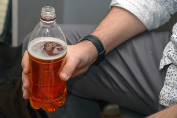 A man holds in his hand a plastic bottle with beer. Drink in a plastic bottle