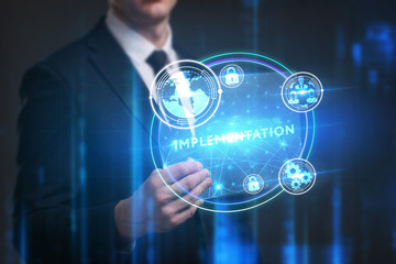Business, Technology, Internet and network concept. Young businessman working on a virtual screen of the future and sees the inscription: Implementation