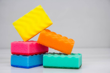 Multicolored sponges for cleaning and washing dishes on a white table. Space for text