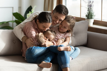 Happy parents having fun with cute children daughters cuddling tickling