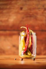 Probiotics food background. Pickled hot pepper chili in glass jars on wooden white background. Copy space