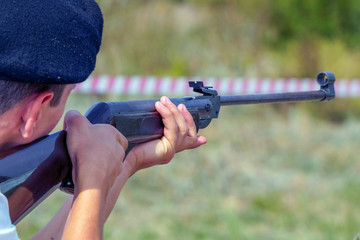 A man in a beret takes aim or shoots with a gun. Back view. Selective focus