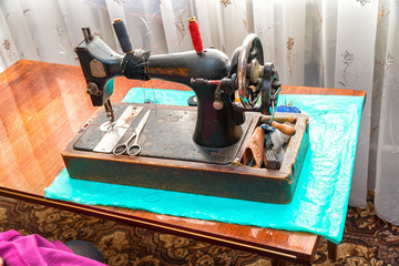 Vintage sewing machine and scissors on the table. Black and white photo