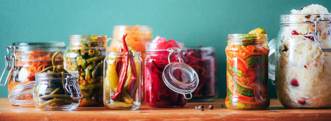 Probiotics food background. Korean carrot, kimchi, beetroot, sauerkraut, pickled cucumbers in glass jars. Winter fermented and canning food concept. Banner with copy space - obrazy, fototapety, plakaty