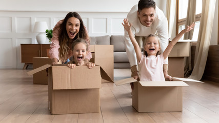Excited family having fun on moving day riding in boxes