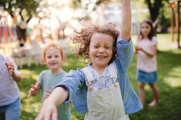 Small children standing outdoors in garden in summer, playing.