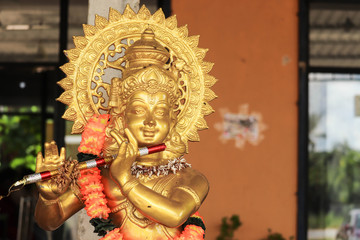 Golden Color Statue Of Lord God Idol Playing Flute With Flower Garland
