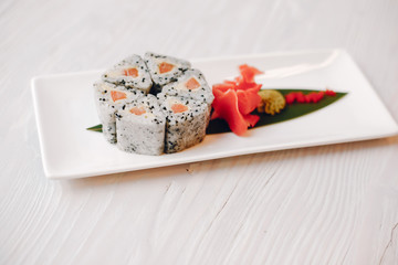Susi are on white background. The table is white. There is a ginger and vasabi.