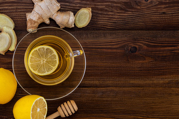 Fototapeta na wymiar Cup of Ginger tea with lemon, honey and ginger root on a wooden background with copy space, top view